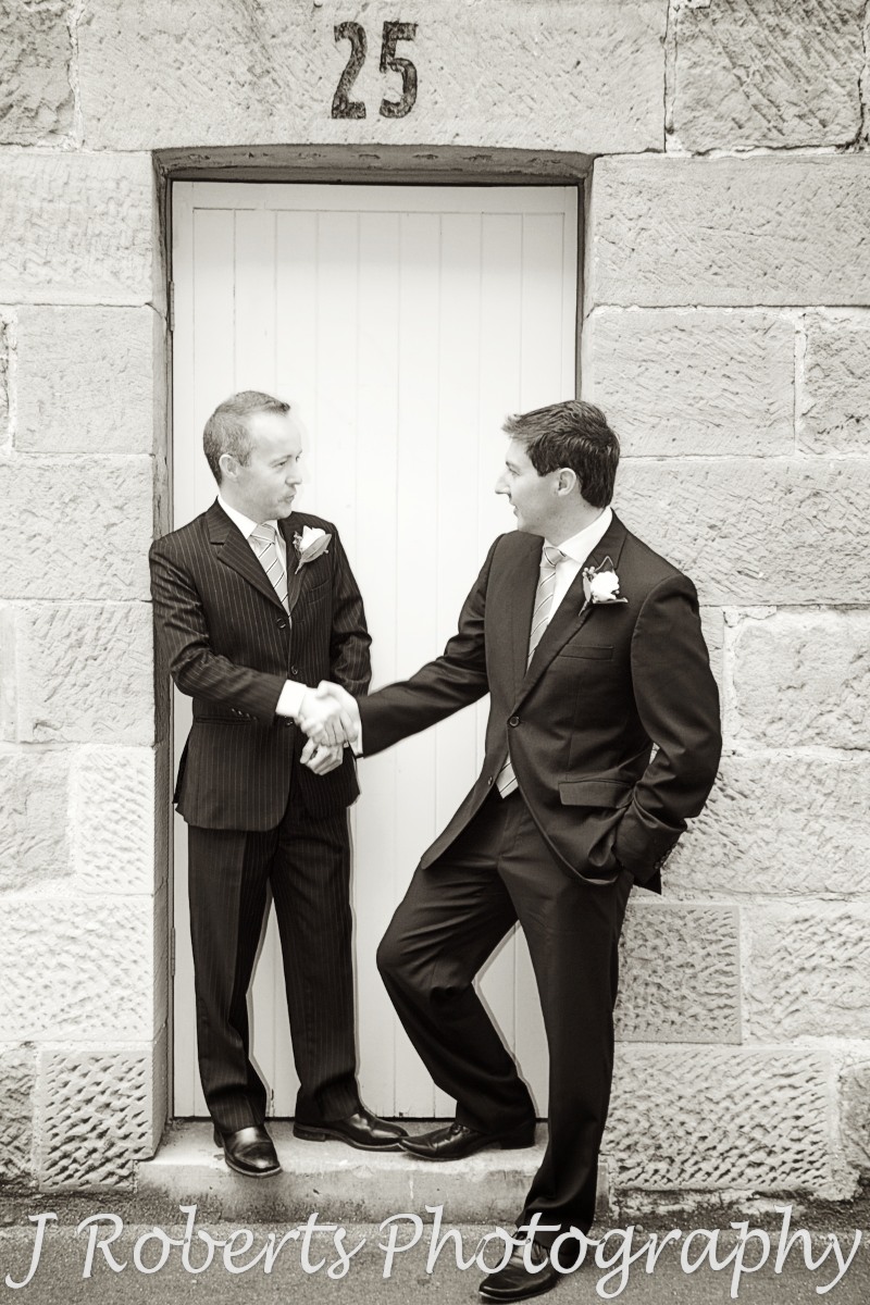 Groom and best man chatting on front of historic doorway the rocks sydney - wedding photography sydney